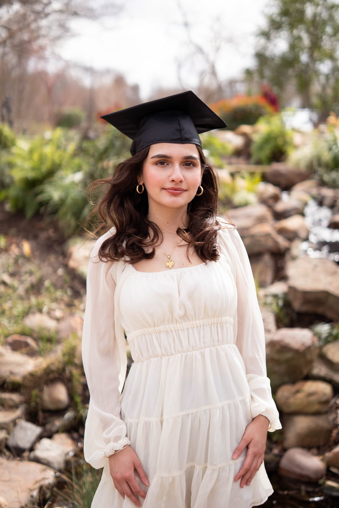 Graduation portrait, young woman in cap and gown at outdoor garden, DFW graduation photographer